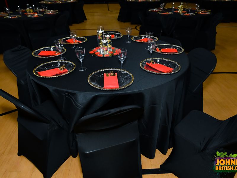 Black and red banquet table setting with gold flatware, beaded charger plates, stemware, and a floating candle centerpiece rented from UniQ51 Party Rentals in Uniondale, NY