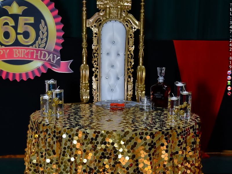 Gold sequin linen cocktail table and white and gold king throne chair rental set against a 65th birthday backdrop at a Nassau County party
