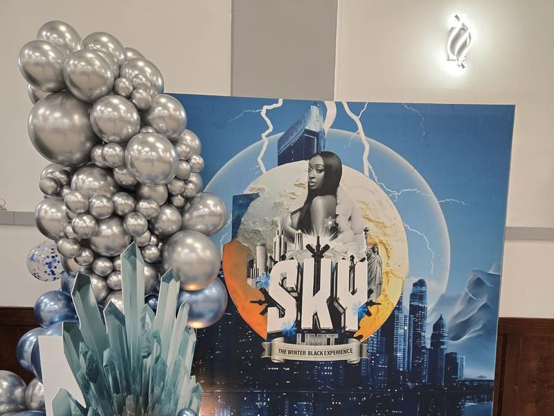 Silver and blue chrome balloon garland with ice crystal cutouts framing a custom winter-themed step-and-repeat photo backdrop and printed floor decal by UniQ51 Photo Booth